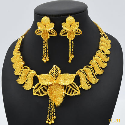 Gold necklace and earrings set on a black mannequin with a gray background