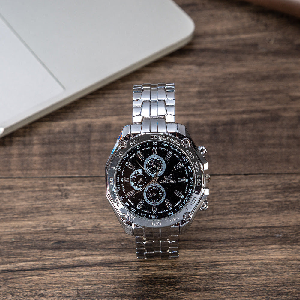 Men's wristwatch with black dial and silver metal bracelet on tabletop.