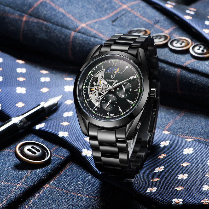 Black men's mechanical watch with open-heart dial and link bracelet on patterned fabric