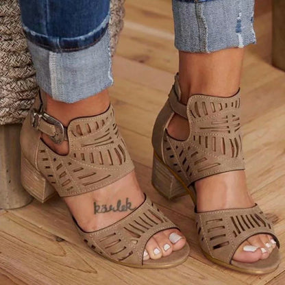 Beige open-toe sandals worn with rolled-up jeans on a wooden floor.