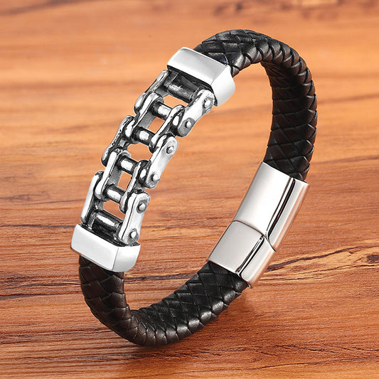 Black braided leather bracelet with silver metal clasp on a wooden surface