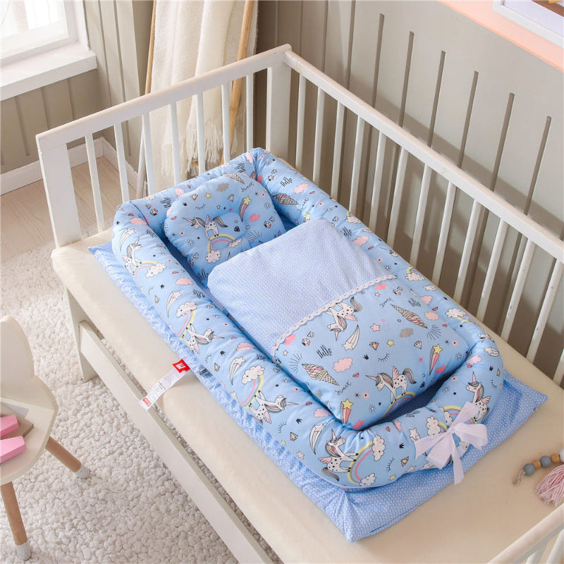 Blue baby nest crib with animal print mattress and matching pillow