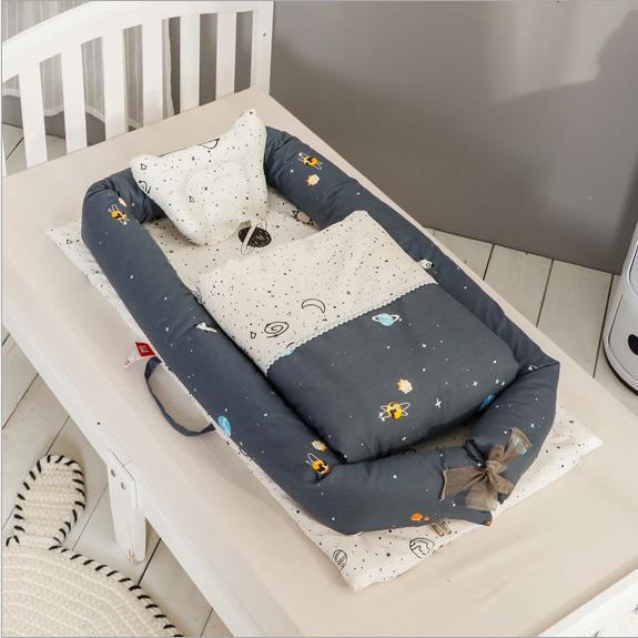 Portable baby nest with dark gray and white animal print mattress and small pillow