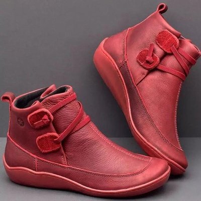 Red leather ankle boots with decorative bows on a gray background