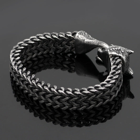 Black braided leather bracelet with a metal clasp on a dark background