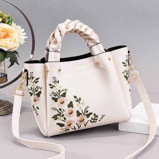 White handbag with floral embroidery on a light gray background