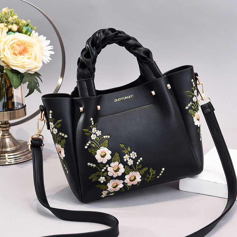Floral PU handbag tote in black with braided handles, gold studs, and crossbody strap
