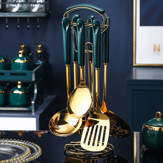 Set of gold and green kitchen utensils on a dark surface with a blurred background