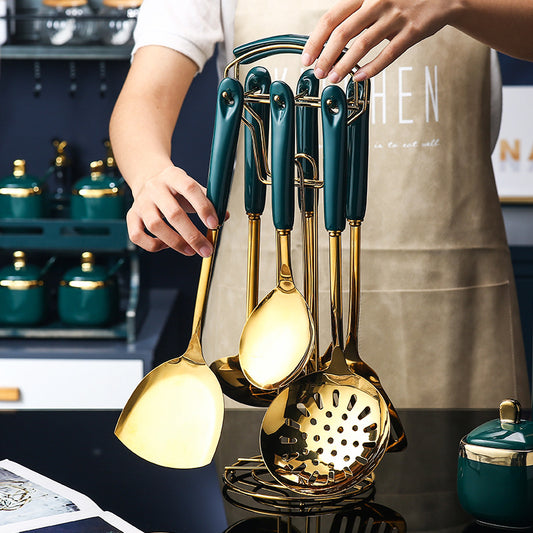 Set of gold kitchen utensils including ladles and a strainer held by a person wearing a beige apron.