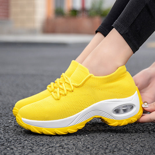 Yellow athletic shoes with white soles worn on a blurred outdoor background