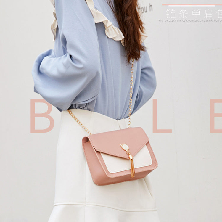 Light pink small square crossbody bag with white flap panel and gold chain tassel charm