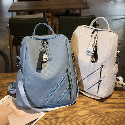 Two backpacks, one blue and one white, on a wooden table with a blurred background.