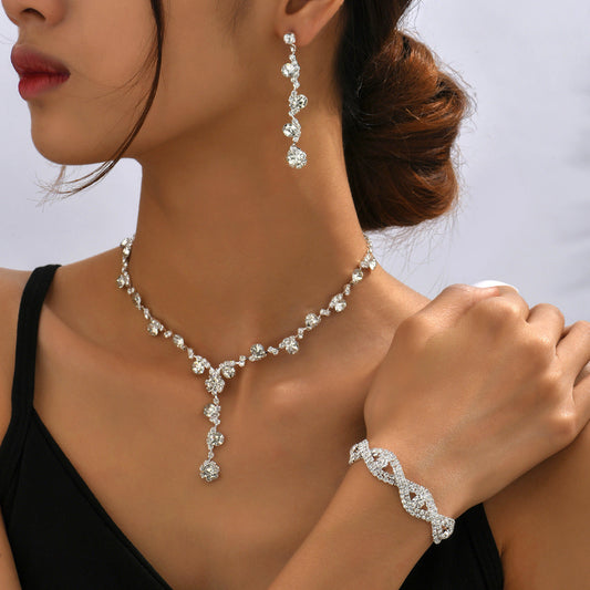Woman wearing a diamond necklace, earrings, and bracelet on a neutral background