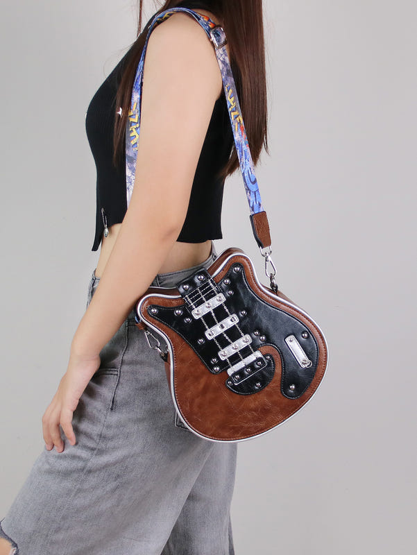 Small guitar-shaped crossbody bag with brown front, black hardware, and patterned strap