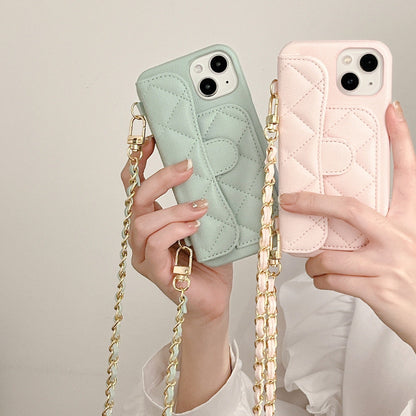 Two phone cases, one green and one pink, held by hands with a gold chain strap.