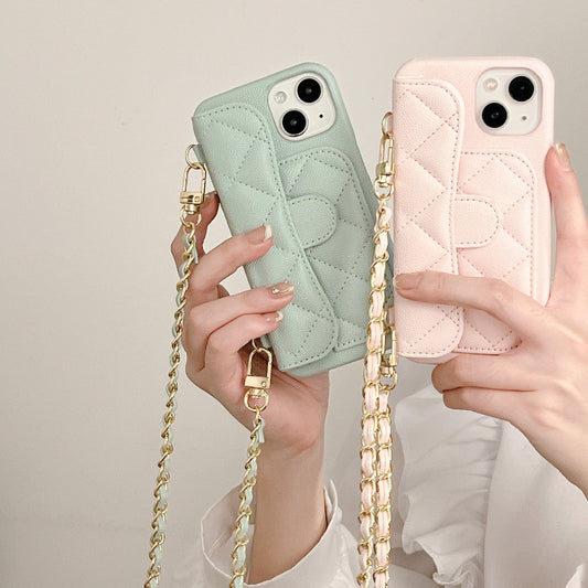 Two phone cases, one green and one pink, held by hands with a gold chain strap.