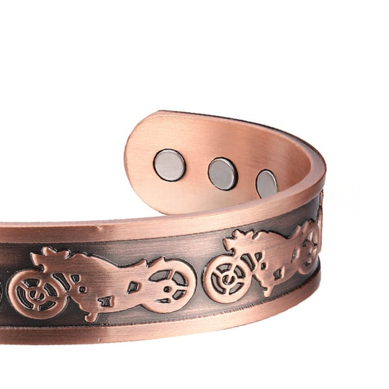 Copper-tone magnetic bracelet close-up with engraved gear motif and three round snap points