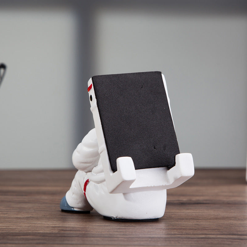 Astronaut mobile phone stand with black back panel and white base, blue shoes