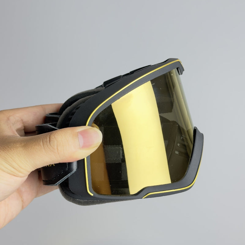 Hand holding a black and gold protective mask against a gray background