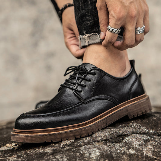 Black leather shoe being worn on a rock with a blurred background