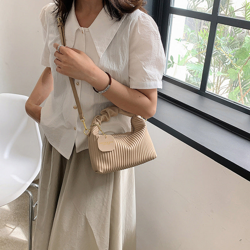 Light beige ribbed PU leather crossbody bag with chain strap and small charm label