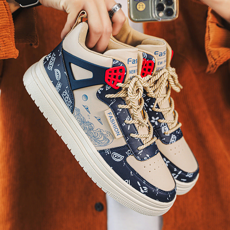 Person holding high-top sneakers; navy patterned leather, beige panels, red lace detail