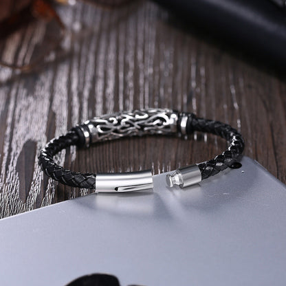 Black braided leather bracelet with silver metal clasp on a wooden surface
