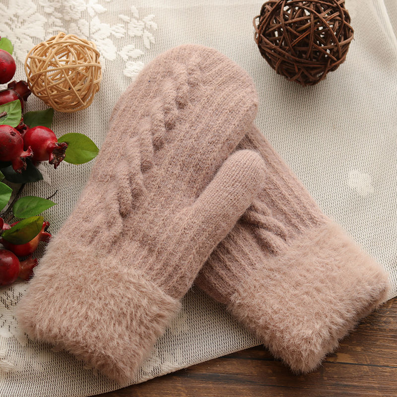 Pair of beige fuzzy gloves on a textured surface with decorative elements.