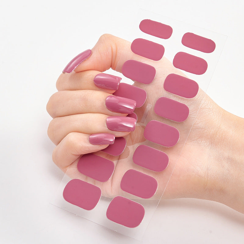 Hand holding pink nail stickers against a white background