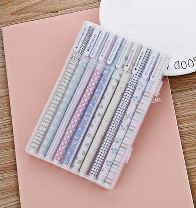 Set of stationery items including pens and a ruler on a pink surface.