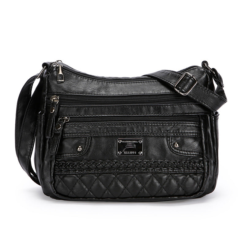 Black quilted handbag with multiple zippers on a white background
