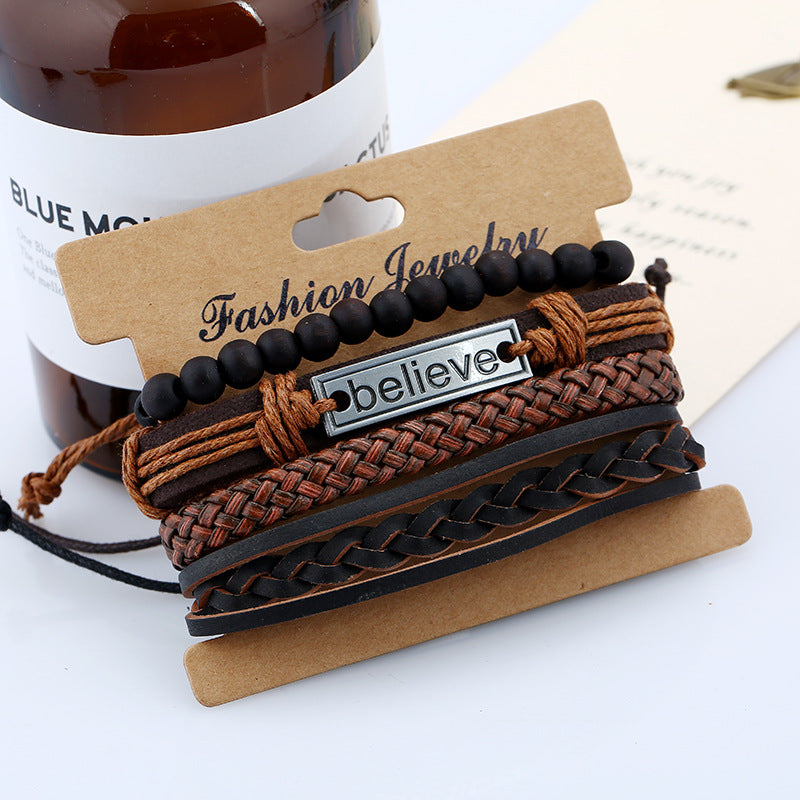 Stack of braided bracelets with a 'believe' tag on a cardboard holder, with a bottle in the background.