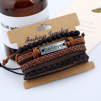 Stack of braided bracelets with a 'believe' tag on a cardboard holder, with a bottle in the background.