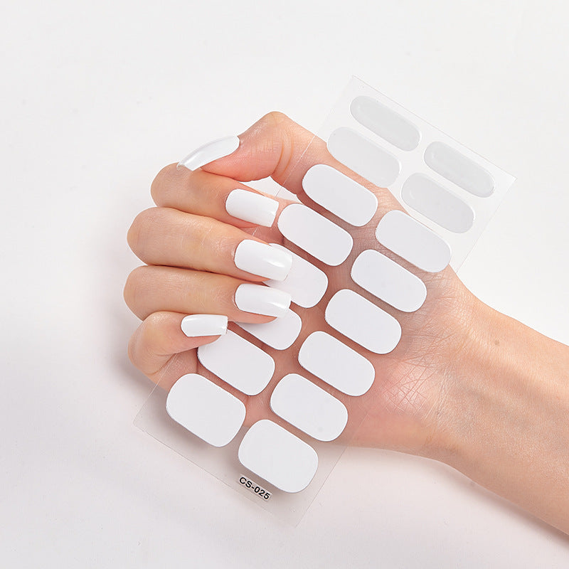 Hand holding a sheet of white nail extensions on a light gray background