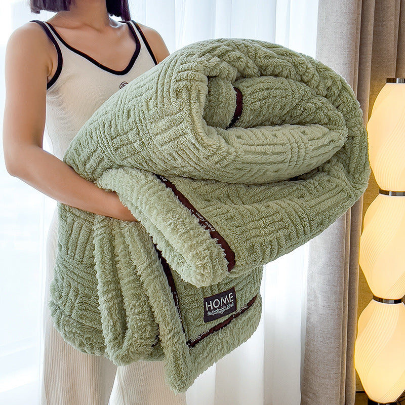 Plush velvet winter blanket in sage green with dark striped edge and stitched logo patch