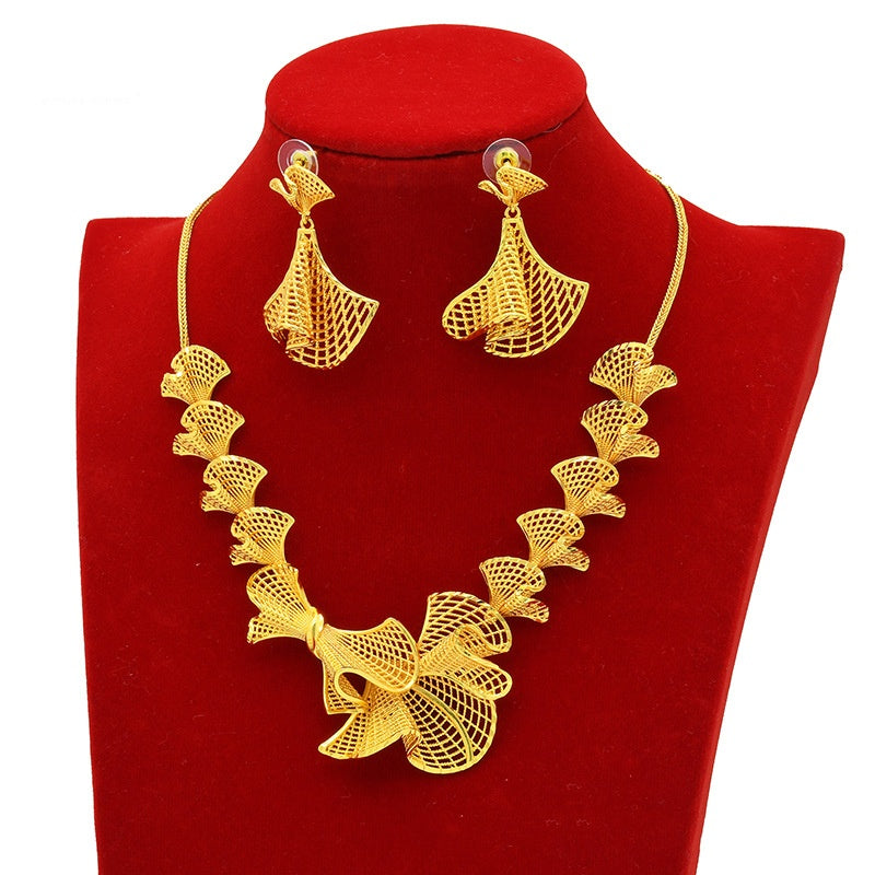 Gold necklace and earrings set on a red stand
