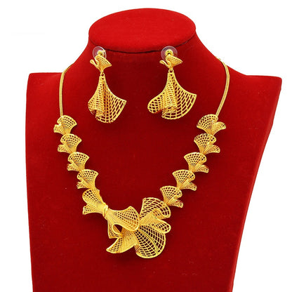 Gold necklace and earrings set on a red stand