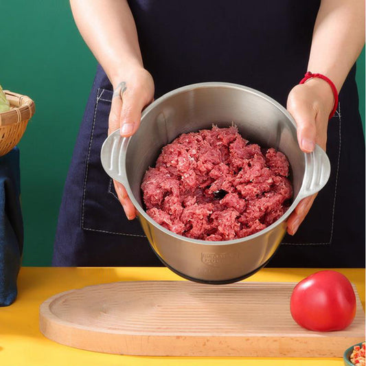 Person holding a metal grinder filled with ground meat on a yellow surface with a green background.