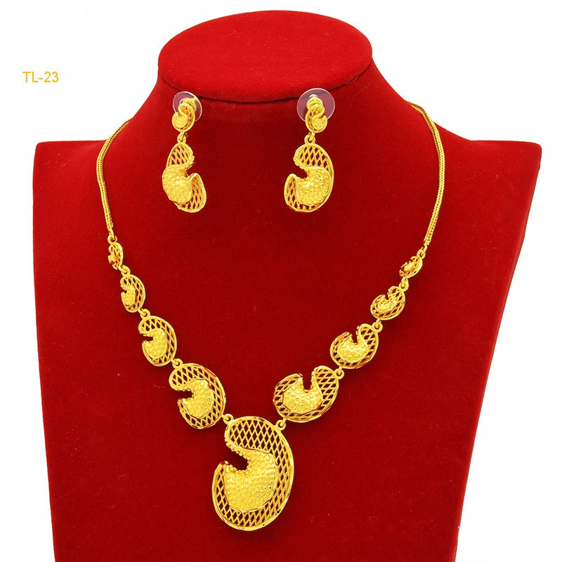 Gold necklace and earrings set on a red stand