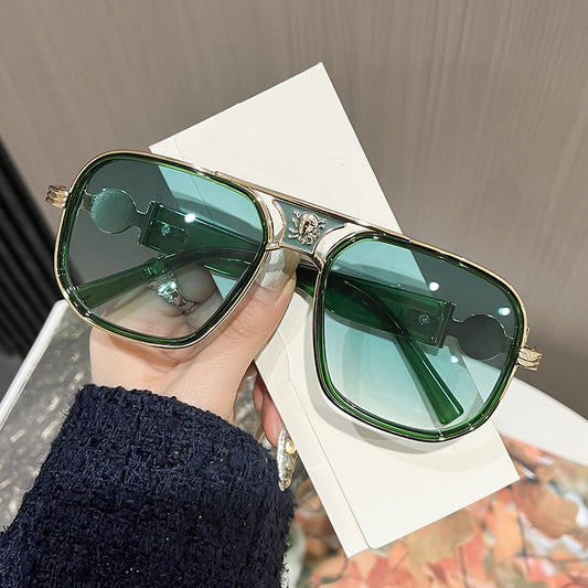 Green sunglasses held by a hand on a textured surface