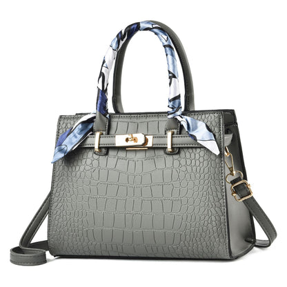 Gray croc-textured tote bag with blue patterned scarf handles and shoulder strap