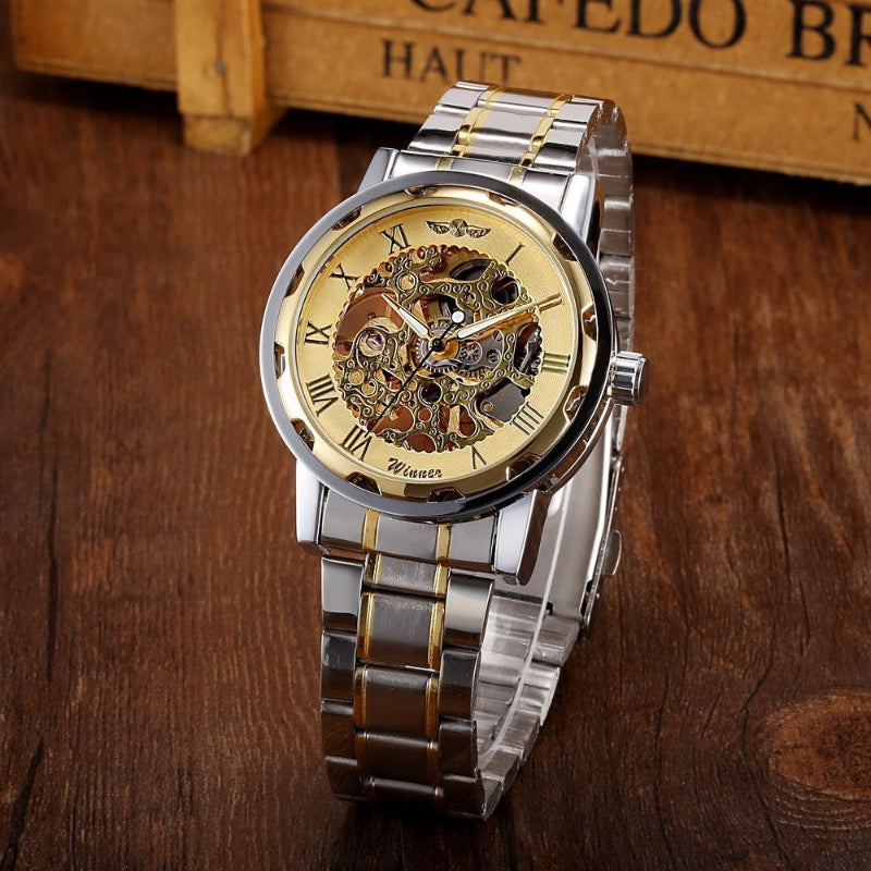 Silver and gold watch with mechanical components on a wooden surface