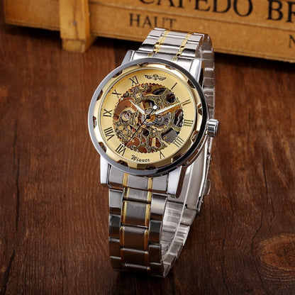 Silver and gold watch with mechanical components on a wooden surface