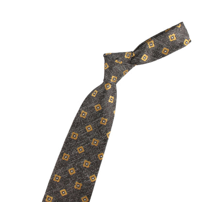 Gray tie with gold patterns and a small violin-shaped object on a white background