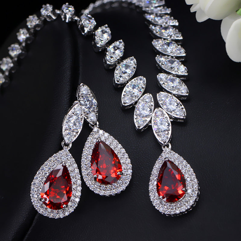 Jewelry set with red teardrop earrings and necklace on a black background