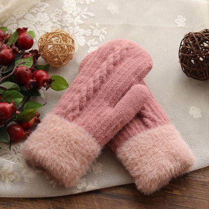 Pink knitted gloves with fluffy cuffs on a decorative surface with flowers and balls.