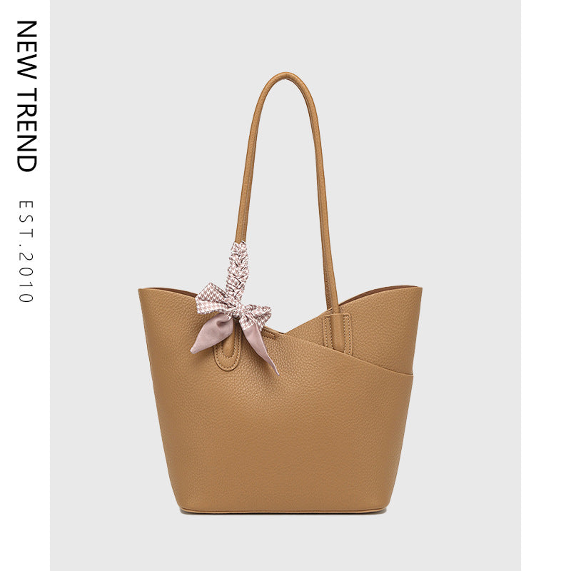 Light tan shoulder tote handbag with bow charm and top handles