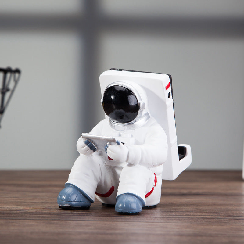 Astronaut mobile phone stand with phone displayed on white helmet, blue shoes