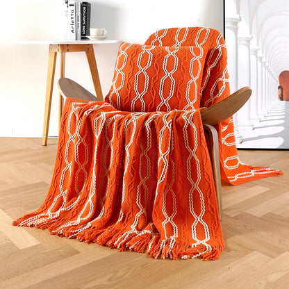 Orange textured blanket draped over a chair in a room with a wooden floor.