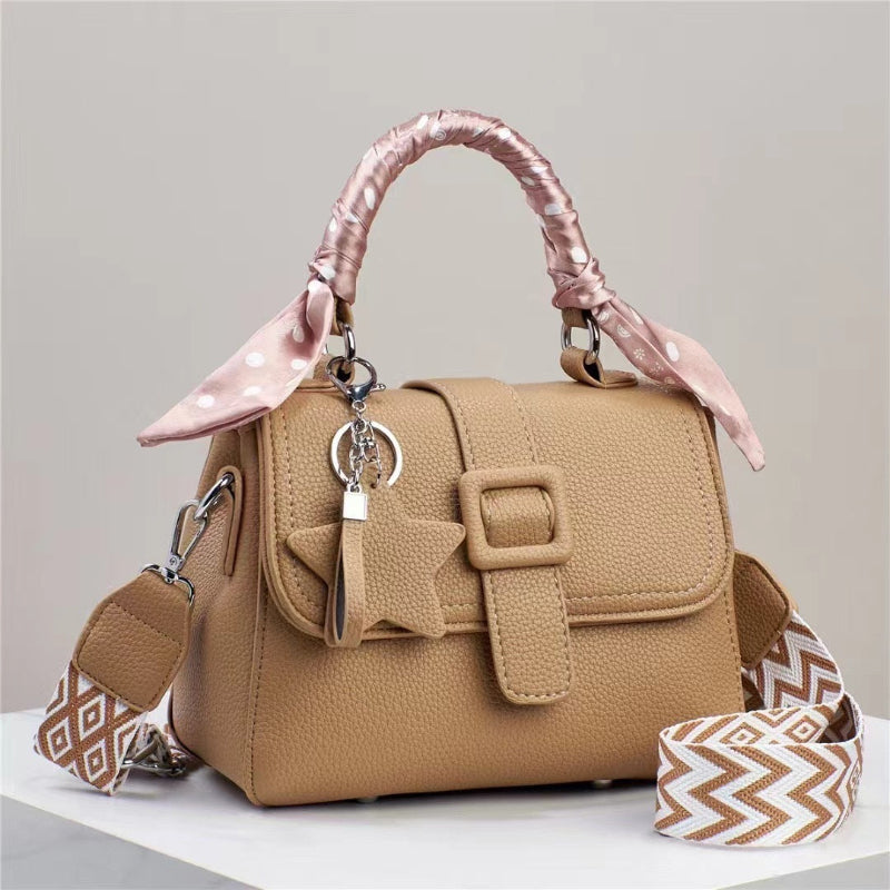 Tan/beige handbag with top flap, front buckle detail, and pink handle scarf